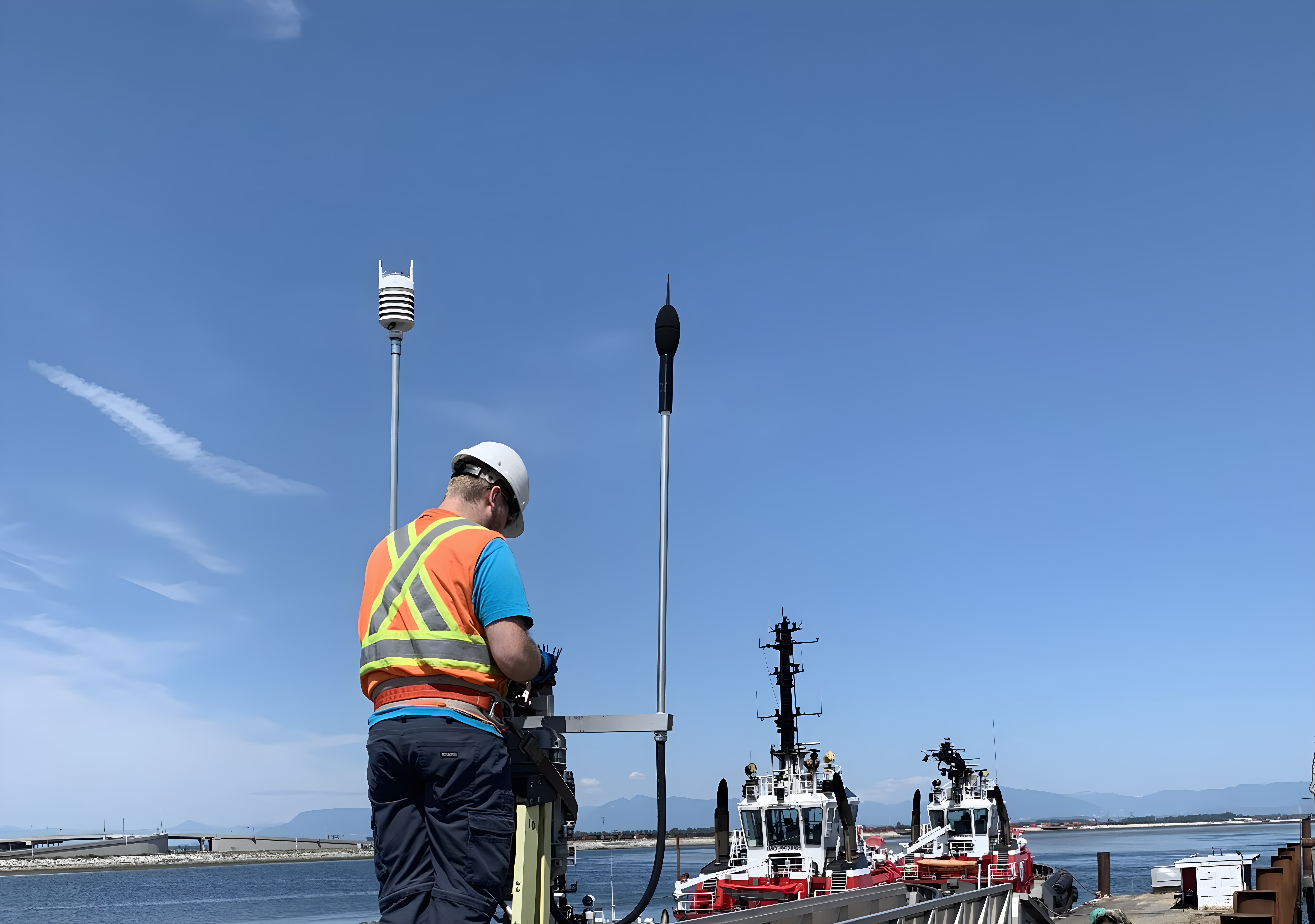 A worker deploying and calibrating monitoring sensors in the field, sound level meter and weather sensor